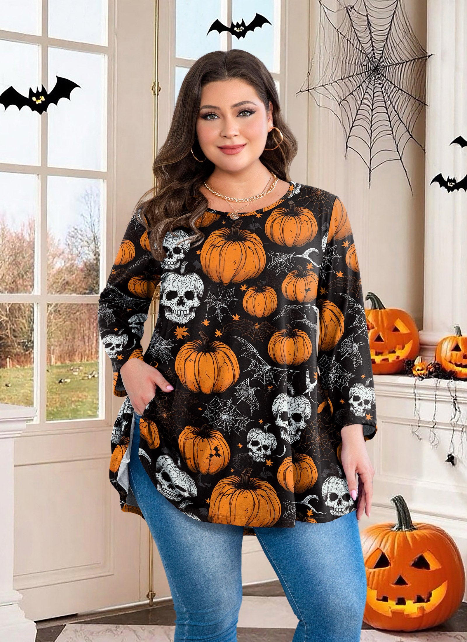 Woman wearing a Halloween-themed shirt with pumpkins and skulls in a decorated room.